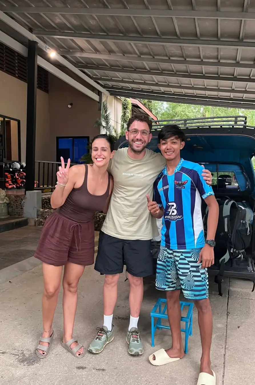 Three smiling travellers posing together under a carport